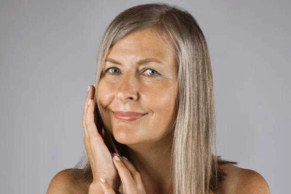 Mature woman with bare shoulders touching gently her cheek — Stock Photo, Image