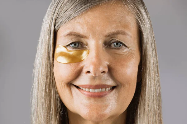 Senior woman posing in studio with collagen eye patches — Stock Photo, Image