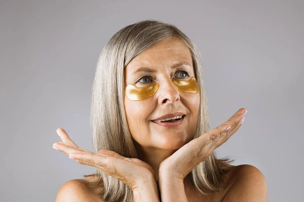 Senior woman posing in studio with patches under eyes — Stock Photo, Image