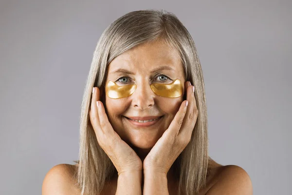 Portrait of aged woman posing in studio with eye patches — Stock Photo, Image