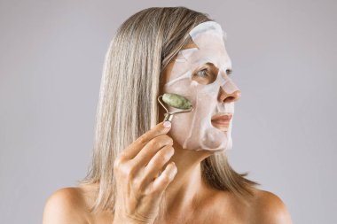 Masaj yapmak için yeşim taşı kullanan olgun bir kadın.