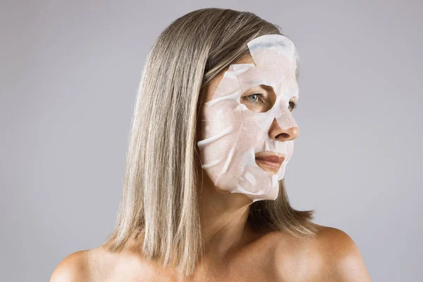 Mature woman with cotton mask on face posing in studio — Stock Photo, Image