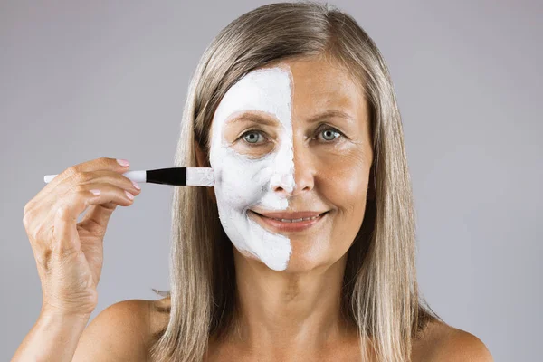 Érett nő alkalmazása maszk fél arc ecsettel — Stock Fotó