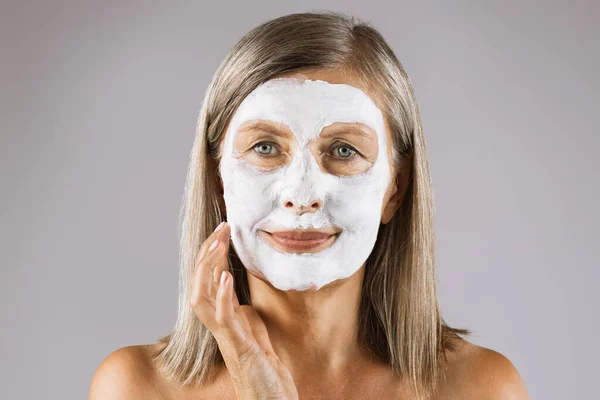 Retrato de mulher idosa com máscara hidratante de argila no rosto — Fotografia de Stock