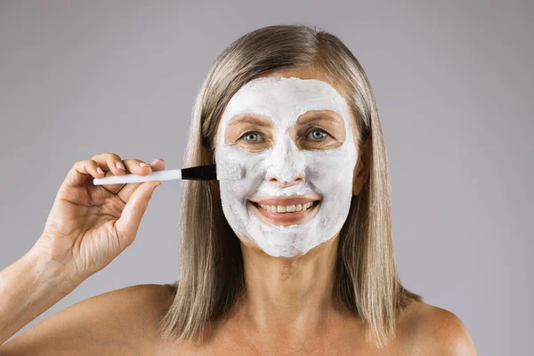 Mature woman with mask on face smiling at camera — Stock Photo, Image