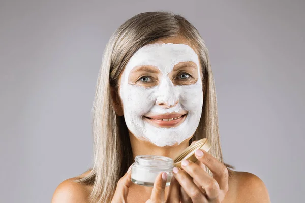 Senior woman with facial skincare mask posing in studio — Stock Photo, Image