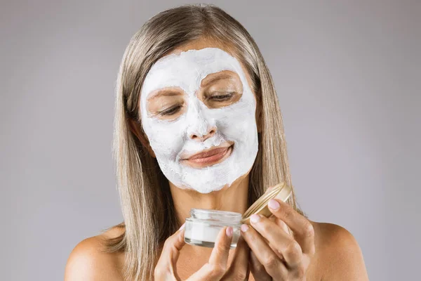Senior woman using cosmetic mask for moisturizing skin — Stock Photo, Image