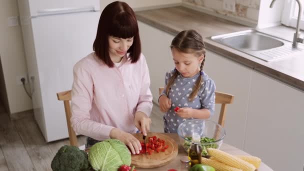 トップビューの母教える小さな未就学児の娘チョップペッパー準備サラダ — ストック動画
