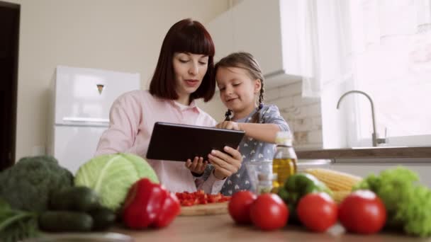 유행하는 세련 된 주부 어머니와 어린 딸 이 새로운 채식 메뉴를 선택하는 도구를 사용하는 모습 — 비디오
