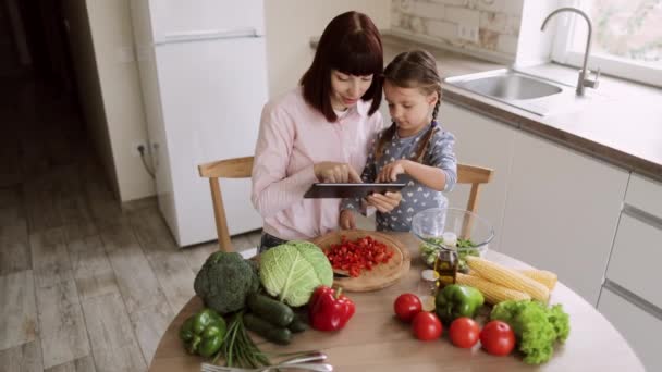 Вид зверху мама і дочка готують разом на кухні, використовуючи чек на планшеті . — стокове відео