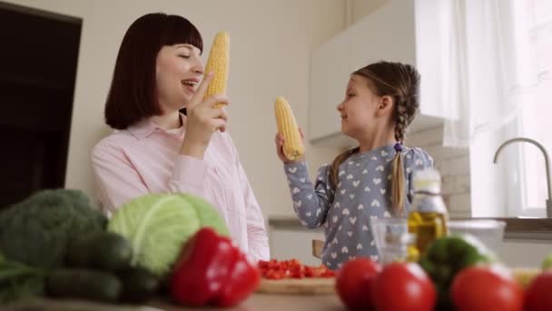 Joven caucásico madre y poco preescolar hija tener divertido mientras lucha usando mazorca de maíz — Vídeos de Stock