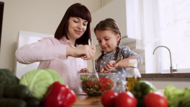 Mother teach caucasian small cute daughter preparing healthy vegetarian food with cutting vegetables — Stock Video