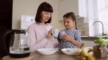 Mutlu gülümseyen bir ailenin portresi. Parlak bir mutfakta hafta sonu kahvaltısı yapıyorlar..