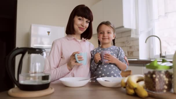 Porträt einer glücklich lächelnden Familie beim Frühstück an einem Wochenendmorgen in einer hellen Küche. — Stockvideo