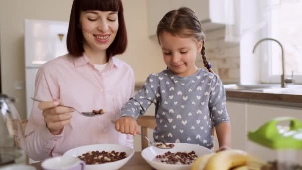 Młody piękny biały matka i jej słodkie mała dziewczynka mając śniadanie z czekolada kukurydza kulki — Wideo stockowe