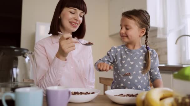 Młody piękny biały matka i jej słodkie mała dziewczynka mając śniadanie z czekolada kukurydza kulki — Wideo stockowe
