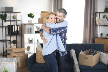 Yeni daireye taşındıktan sonra kucaklaşan mutlu ve olgun bir çift.