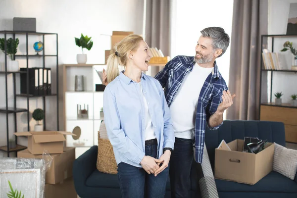 Pareja feliz hombre y mujer de pie en sus nuevos departamentos acogedores después de un acuerdo exitoso de bienes raíces. — Foto de Stock