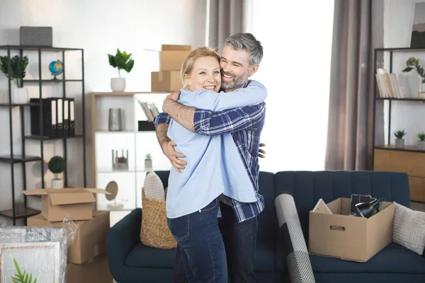 Feliz pareja madura abrazando y feliz después de la reubicación a nuevo apartamento — Foto de Stock