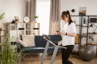 Beyaz tişörtlü sporcunun yan görüntüsü cep telefonu uygulaması kullanarak antrenmanı ısıt