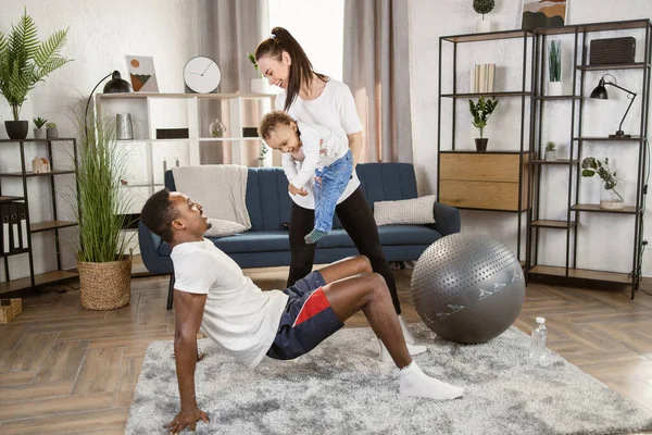 Familia multirracial motivada haciendo ejercicio juntos en casa, hombre africano y mujer caucásica con hijo — Foto de Stock