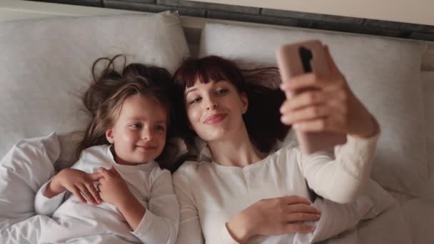 Top widok młodej pięknej matki i jej cute córka biorąc selfie ze smartfonem. — Wideo stockowe