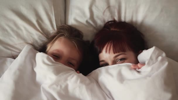 아름다운 젊은 여성들 과 그 의 딸 이 침대에 누워서 카메라를 보고 놀라는 모습 — 비디오
