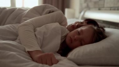 Güzel, genç, beyaz, anne kadın. Sağlıklı, tatlı kızıyla yatakta yatıyor.