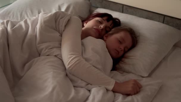 Una buena chica y su madre disfrutan de la mañana soleada mientras duermen juntos. — Vídeos de Stock