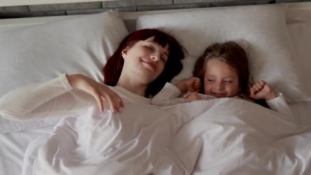Matka i córka cieszą się czasem na łóżku podczas rozciągania po przebudzeniu. — Wideo stockowe