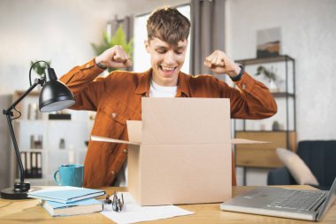 Mutlu erkek blogcu paketleri evde açıyor.