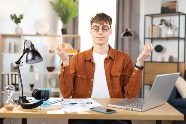 Kafkasyalı rahat bir adam iş yerinde meditasyon yapıyor.