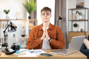 Kafkasyalı rahat bir adam iş yerinde meditasyon yapıyor.