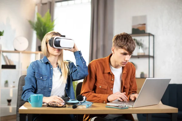 Joyeux jeunes amis assis à la table et utilisant des gadgets modernes pour le travail ou l'étude — Photo