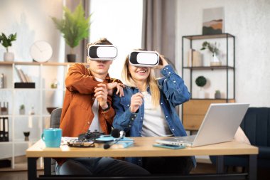 Genç arkadaşlar VR kulaklıklarıyla masada oturup 3 boyutlu gerçekliğin tadını çıkarıyorlar.