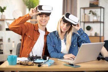 Genç çift oyun oynamak için VR kulaklık ve dizüstü bilgisayar kullanıyor