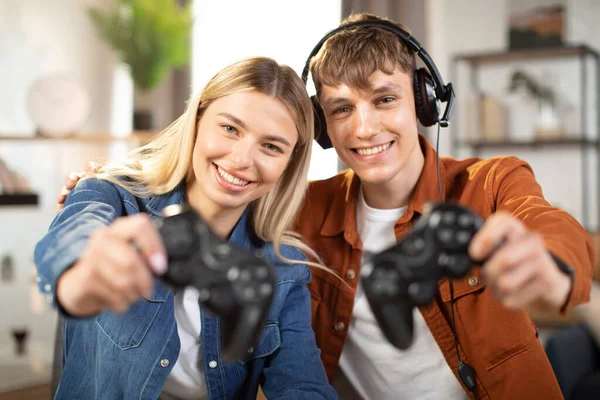 Handsome man and pretty blond woman, showing wireless joysticks to camera — Foto de Stock