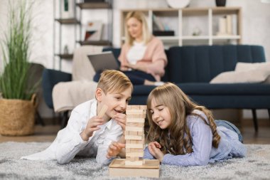 Küçük çocuklar, ahşap yapı taşları ile bir kule inşa ederek oyun oynarlar.