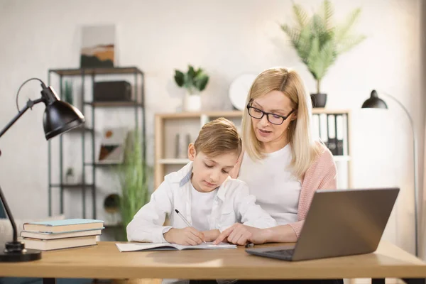 Moeder helpen zijn zoon met zijn huiswerk thuis. — Stockfoto