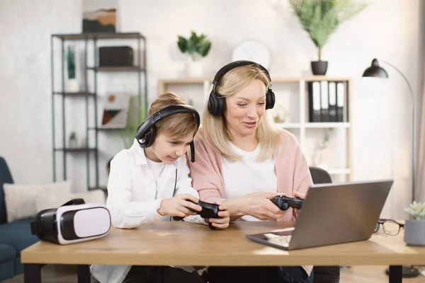 Mutlu genç anne ve heyecanlı küçük oğlu bilgisayarlarında joysticklerle sanal video oyunu oynuyorlar. — Stok fotoğraf