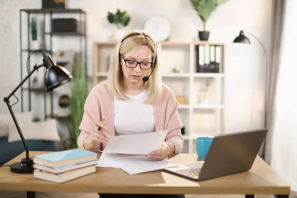 Confident mature woman taking notes while typing on laptop at office. —  Fotos de Stock