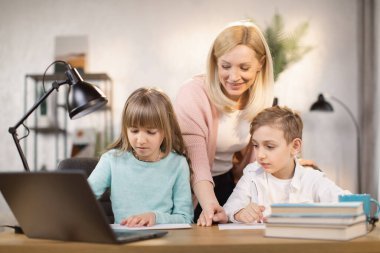 Kızı ve oğlu birlikte ders yapıyor. Dizüstü bilgisayara bakıyorlar..