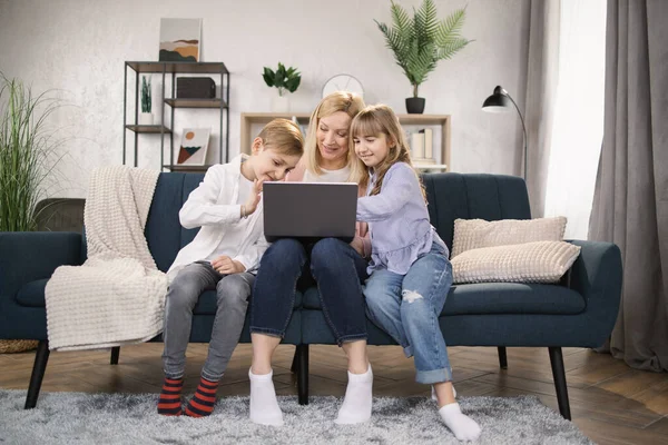 Gelukkig gezin met twee kinderen hebben veel plezier met behulp van laptop. — Stockfoto