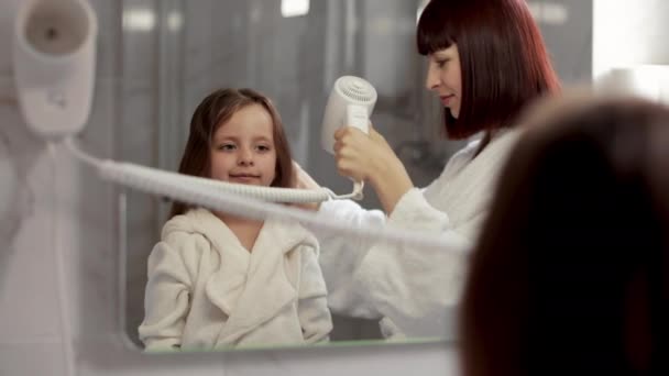 Mother is brushing and drying child hair after shower standing in front of a mirror in the bathroom — Stock videók