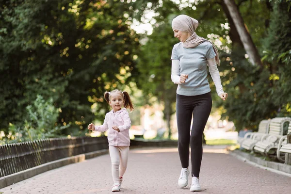 Μουσουλμάνα Αραβίδα που απολαμβάνει να τρέχει μαζί στο πάρκο με την χαριτωμένη ενεργή 4χρονη κόρη της. — Φωτογραφία Αρχείου