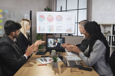 Dört yetenekli çok ırklı iş adamından oluşan bir grup el çırpıyor ve dizüstü bilgisayara bakıyor.