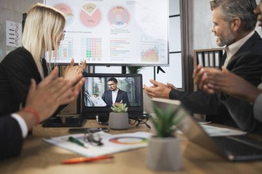 Dört yetenekli çok ırklı iş adamından oluşan bir grup el çırpıyor ve dizüstü bilgisayara bakıyor.