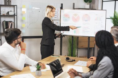 Güzel, motive olmuş, zeki, sarışın, genç iş kadını dijital panoda bilgi paylaşımı yapıyor.