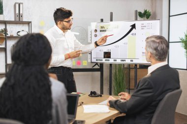 Karışık ırk iş adamlarından oluşan bir ekip orta yaşlı Hintli erkek şeflerini dinliyor.