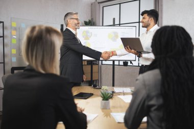 Kıdemli profesyonel işadamı Hintli yöneticiye elini sıkıyor.